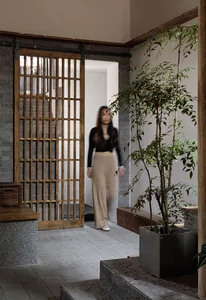 Cozy residential interior with a brick wall, a bench, potted plants, and a vase, suggesting a welcoming living area
