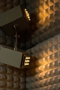 A modern bathroom with a tile wall featuring a mirror on one side and lights on the other, with two lights and a clean, well-lit atmosphere