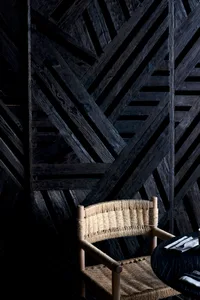 A wooden chair with a straw-like pattern on its backrest sits in front of a wall in a warm and inviting dining area