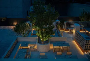 A patio area with tables and chairs arranged around a central tree, creating an inviting space for dining and socializing