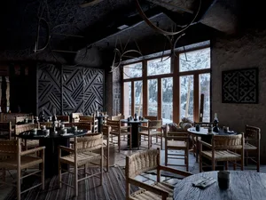 A cozy indoor dining area with multiple tables and chairs, natural light, and a warm ambiance