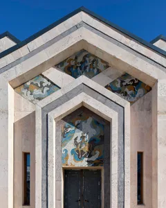 Ornate stone building with a grand archway, gray and white tones, and intricate designs on the walls