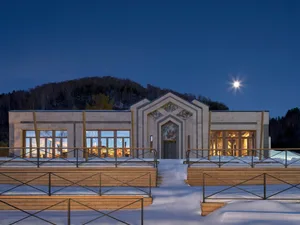 A rendered hotel building with a mix of wood and stone elements, featuring multiple rooms, windows, and a blend of traditional and modern styles