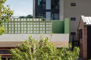 A modern building with multiple levels, a rooftop terrace, and concrete construction, featuring ample natural light through numerous windows
