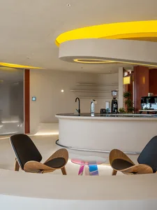 A modern cafe interior with a circular bar and two chairs, surrounded by potted plants and a welcoming atmosphere