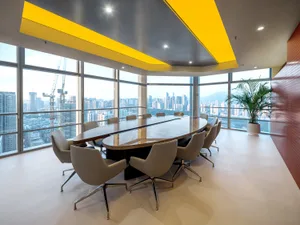 Professional office space with a large table, chairs, and a yellow accent wall, creating a welcoming atmosphere for business meetings