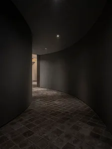 寧靜而吸引人的酒店走廊，具備弧形設計、石牆，以及通往私人房間的門