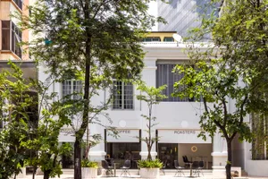 A coffee shop with a white facade, outdoor seating, and dining tables, creating a relaxed atmosphere