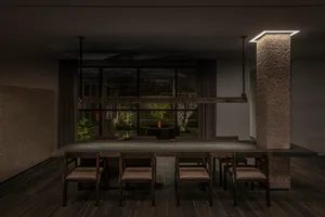 A well-lit dining area with a large wooden dining table surrounded by multiple chairs, creating a comfortable atmosphere for meals and gatherings