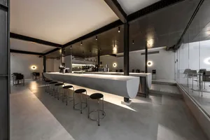 Industrial kitchen with a long concrete countertop, stools, and chairs, in a modern space with a focus on functionality and efficiency