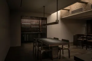 Elegant dining space with a large wooden table surrounded by chairs, wine glasses, and high-quality materials