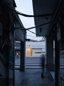 A casual home office space with a white building, doorway, and window, featuring a person and their dog walking through the area