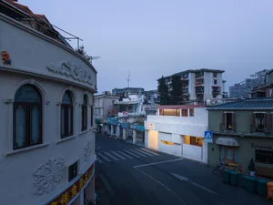夜晚熱鬧的亞洲城市街道，混合住宅與商業大樓，有行人與車輛，以及帶有拱門的裝飾白色建築