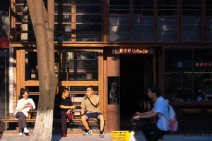 casual outdoor coffee shop with wooden exterior, people sitting on benches and riding bicycles