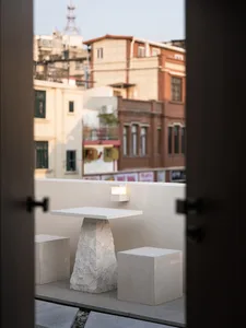Cozy outdoor seating area with a concrete table and chairs on a rooftop or balcony overlooking a city street