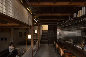A modern bar area with wooden floors and walls, featuring chairs and dining tables, creating a warm and inviting atmosphere