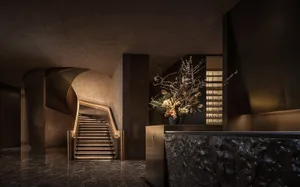 Spiral marble staircase in a luxurious lobby with a large vase on a table, surrounded by high-end design and decoration