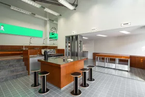Industrial kitchen with a countertop, appliances, stools, and a clean, well-organized atmosphere