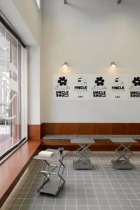 Warm and inviting restaurant interior with wooden walls, a dining area, and a window, featuring artwork and a book