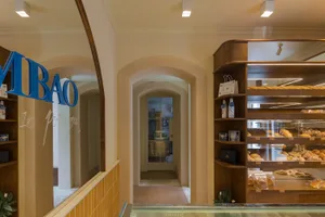 A warm and inviting bakery interior with bread, cakes, and bottles on display