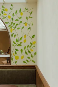 A cozy living area with a tree-painted wall, chairs, and vases, creating a warm and inviting atmosphere