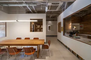 Open modern dining space with a wooden table and brown chairs in a white room with a clean and bright appearance