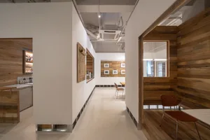 A clean and organized room with white walls, wooden floors, a chair, a dining table, and a second chair