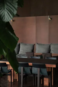 A wooden table surrounded by multiple chairs in a cozy restaurant dining area, set up for a meal with a warm and inviting atmosphere