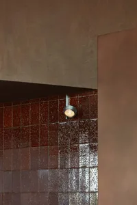 Warm bathroom with red brick walls, brown tile floor, and two overhead lights