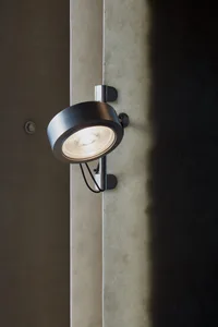 A modern interior space with a minimalist aesthetic, featuring a wall-mounted light fixture casting a shadow on the wall, creating a contrast between lit and darker areas