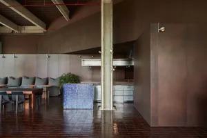 Modern kitchen with a dining table, chairs, refrigerator, sink, and potted plant, with a focus on comfort and inviting atmosphere