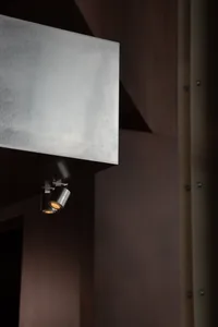 A modern restaurant interior wall with a steel surface, a light fixture, and minimal decoration