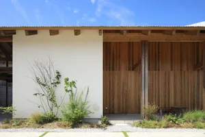 A house with a wooden exterior, featuring two doors, potted plants, and a calm atmosphere