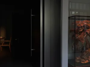 A museum-style hallway with a glass case displaying artwork and sculptures, set against a neutral background