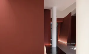 Narrow modern hallway with red walls, a white pillar, and natural light from a window