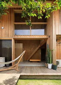 Open living area with wood floors and walls, featuring a hammock, potted plants, and a bicycle, creating a relaxed and inviting atmosphere