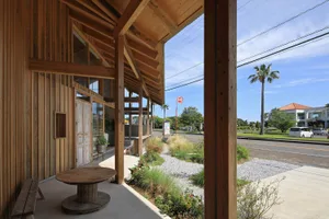 An inviting outdoor patio area with wooden elements, benches, and a dining table, well-lit by natural sunlight