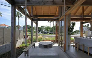 Open living area with wood flooring, white walls, and natural light, featuring a dining table, chairs, and a bench