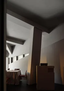 Dimly lit dining room with a wooden dining table and chairs, surrounded by white walls and warm lighting