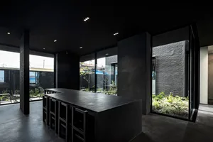 Modern kitchen with a large dining table, potted plants, and a minimalist aesthetic