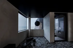 Open living area with concrete walls, black and white color scheme, and natural light from two windows