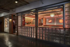Cozy bar area with a long wooden counter lined with glass blocks, surrounded by chairs and a warm atmosphere