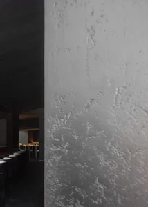 Empty dark room with a concrete wall and several chairs, giving a moody atmosphere