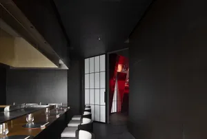 Empty restaurant interior with black walls, red doorway, and chairs placed around the dining area