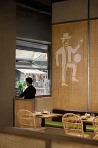 Casual restaurant interior with a counter and dining area featuring chairs, tables, and various tableware