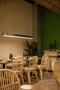 Warm dining space with a long wooden table surrounded by chairs, wine bottles, and a cozy atmosphere