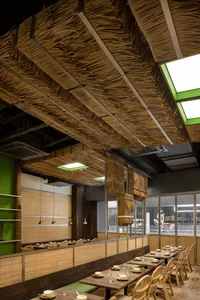 A modern restaurant interior with wooden walls and ceiling, featuring multiple dining tables and chairs in a warm and inviting atmosphere