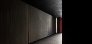 Empty gray hallway with concrete walls, a red door, and a calm atmosphere
