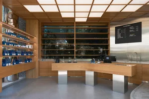 Cozy coffee shop interior with wooden floors and walls, featuring tables, potted plants, and various items, creating a warm and inviting atmosphere