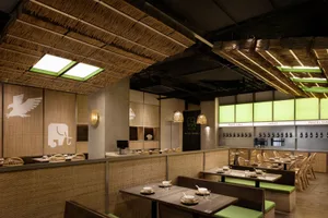 Warm and inviting Asian restaurant interior with wooden walls and ceiling, featuring dining tables and chairs, set up for customers to enjoy meals in a cozy atmosphere